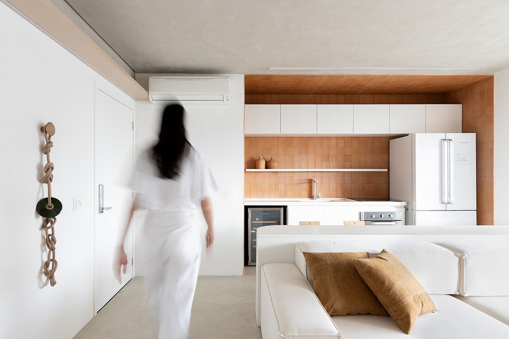 Modern, minimalist kitchen with wood paneling and appliances; person in white dress walks in foreground.