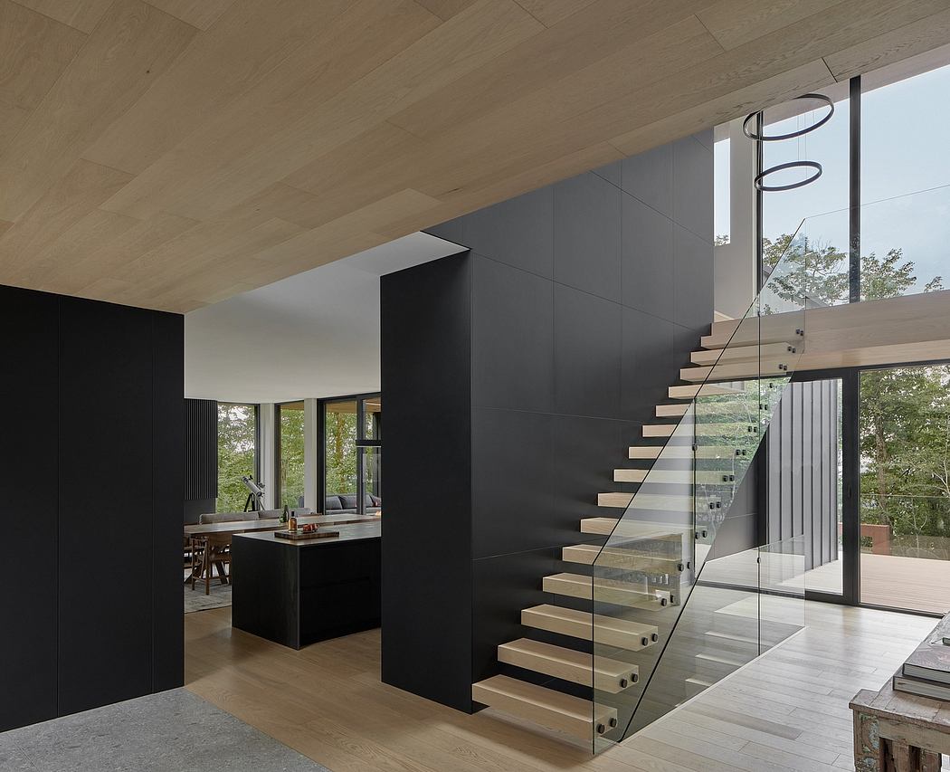 Sleek, minimalist interior with dark walls, floating wood stairs, and expansive windows.