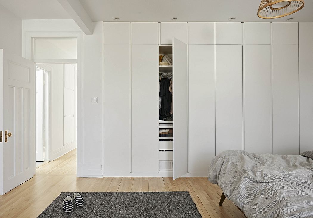 Spacious bedroom with minimalist white built-in closets, hardwood floors, and a pendant light.