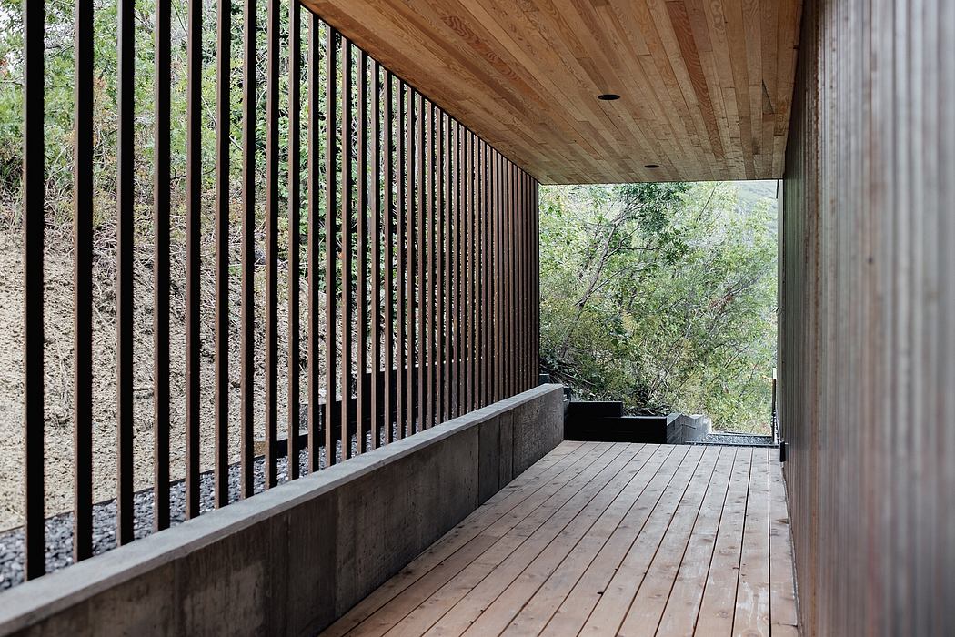 A covered wooden walkway with vertical slats overlooking a forested area.