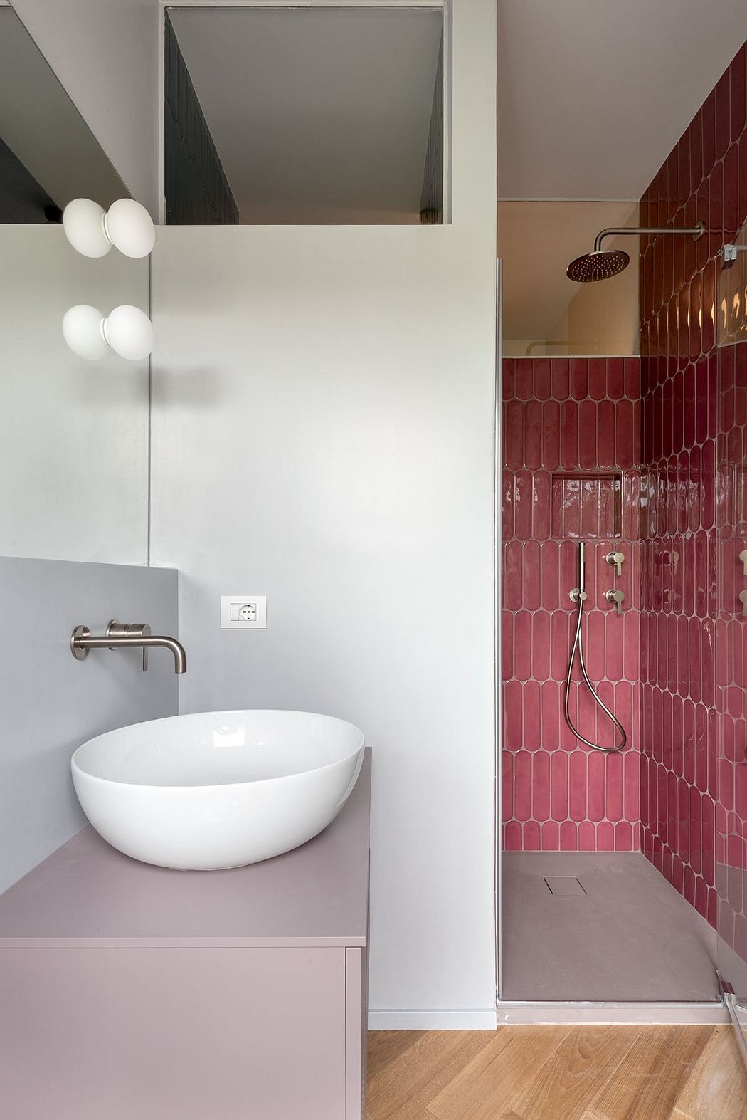 Modern bathroom with white sink, pink tile wall, and minimalist lighting fixtures.