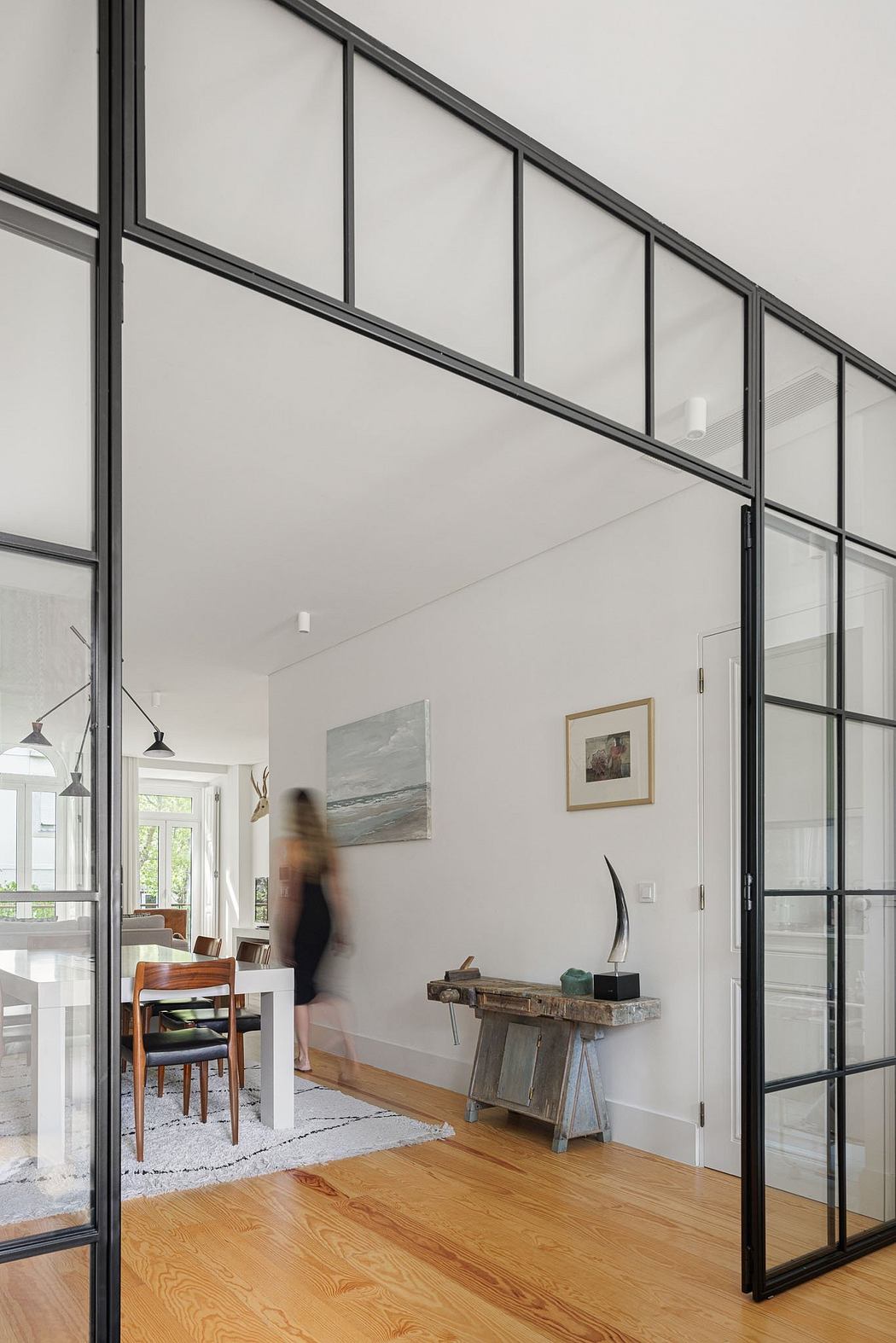 A modern interior with glass walls, wooden floors, and a rustic console table.