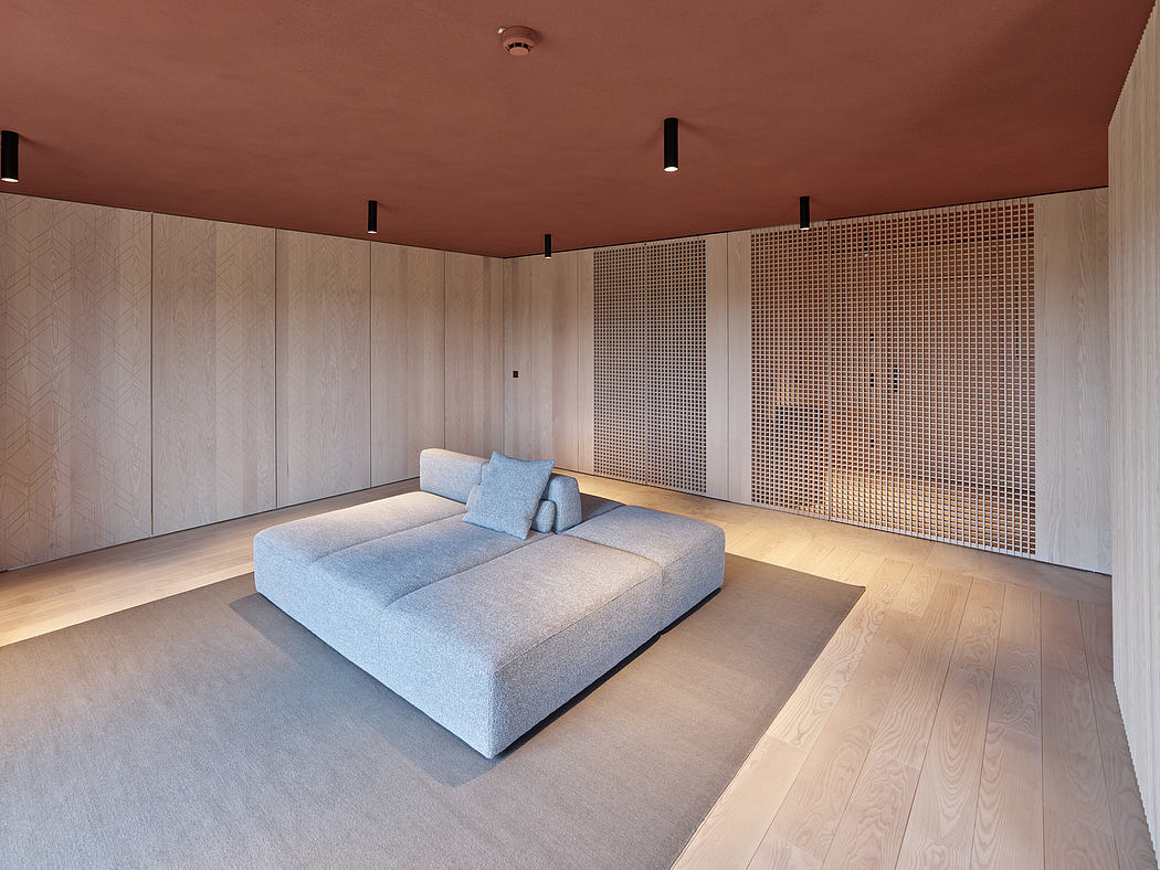 Minimalist interior design featuring a plush gray sofa, wood-paneled walls, and geometric lighting.