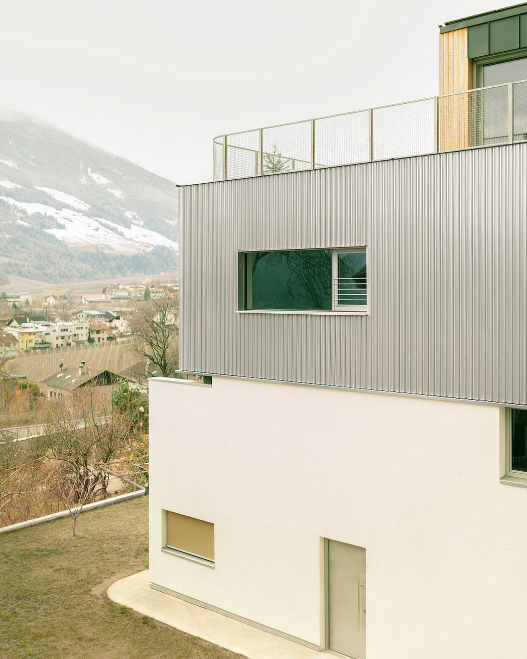 Modern building with green accents, glass panels, and a panoramic mountain view.