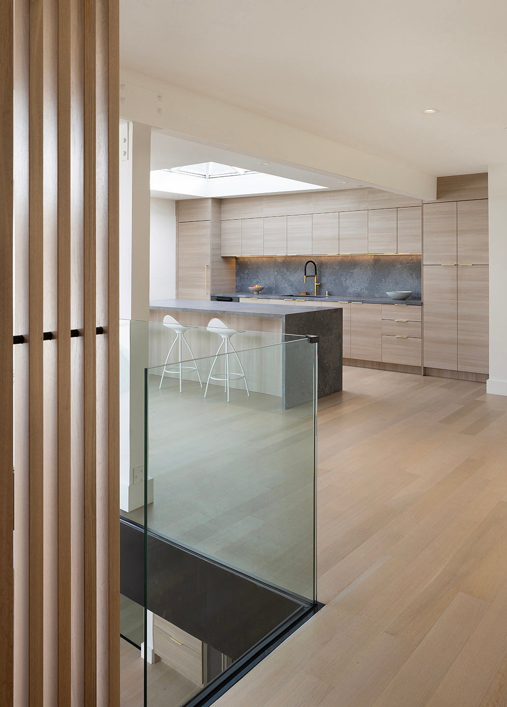 Sleek, modern kitchen with glass partition, wood accents, and minimalist design.