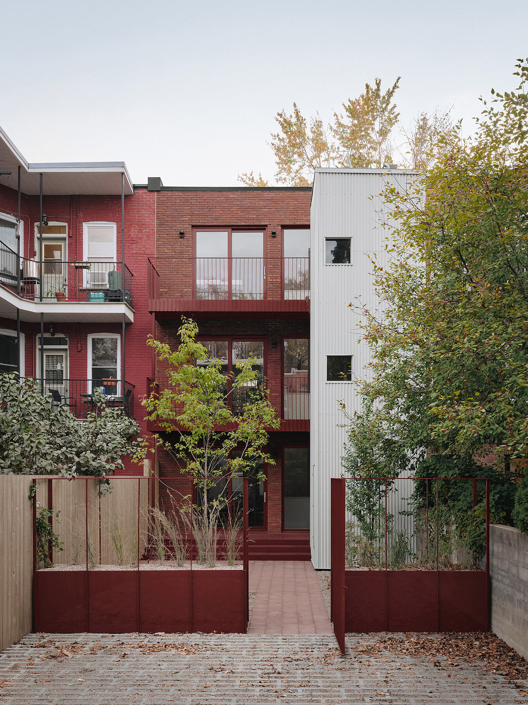Red brick and white facade buildings with balconies, surrounded by trees and greenery.