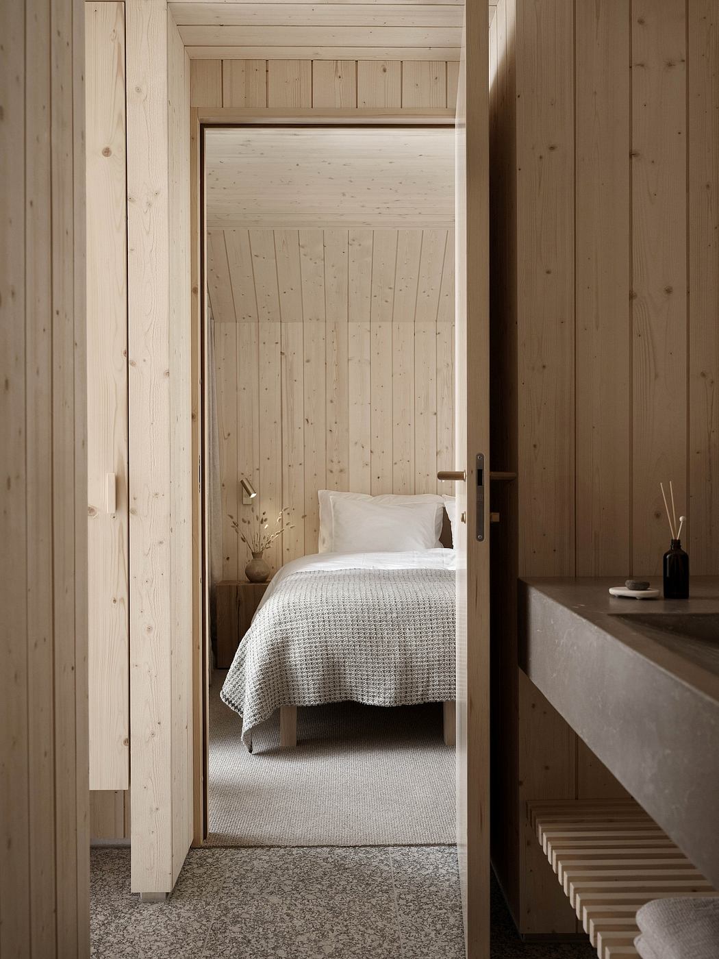 Cozy wooden bedroom with textured walls, a simple bed, and minimalist decor.