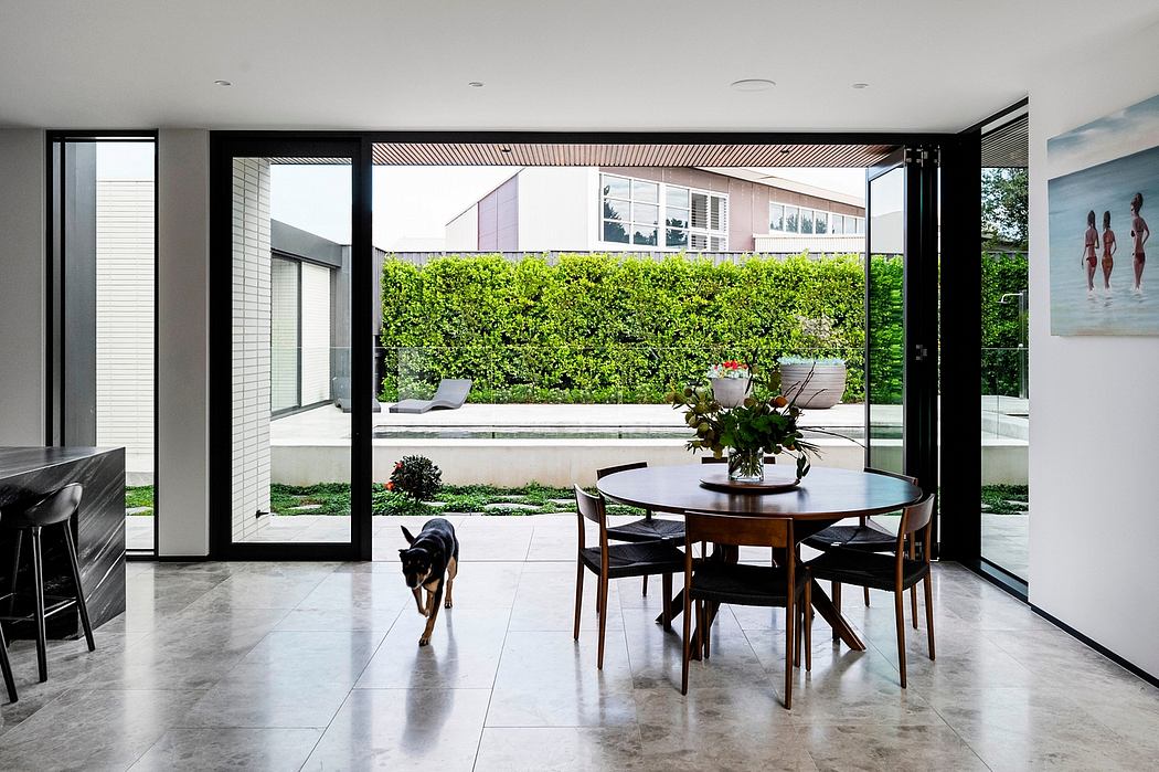 Modern open-concept dining area with sleek furniture, floor-to-ceiling windows, and lush greenery.