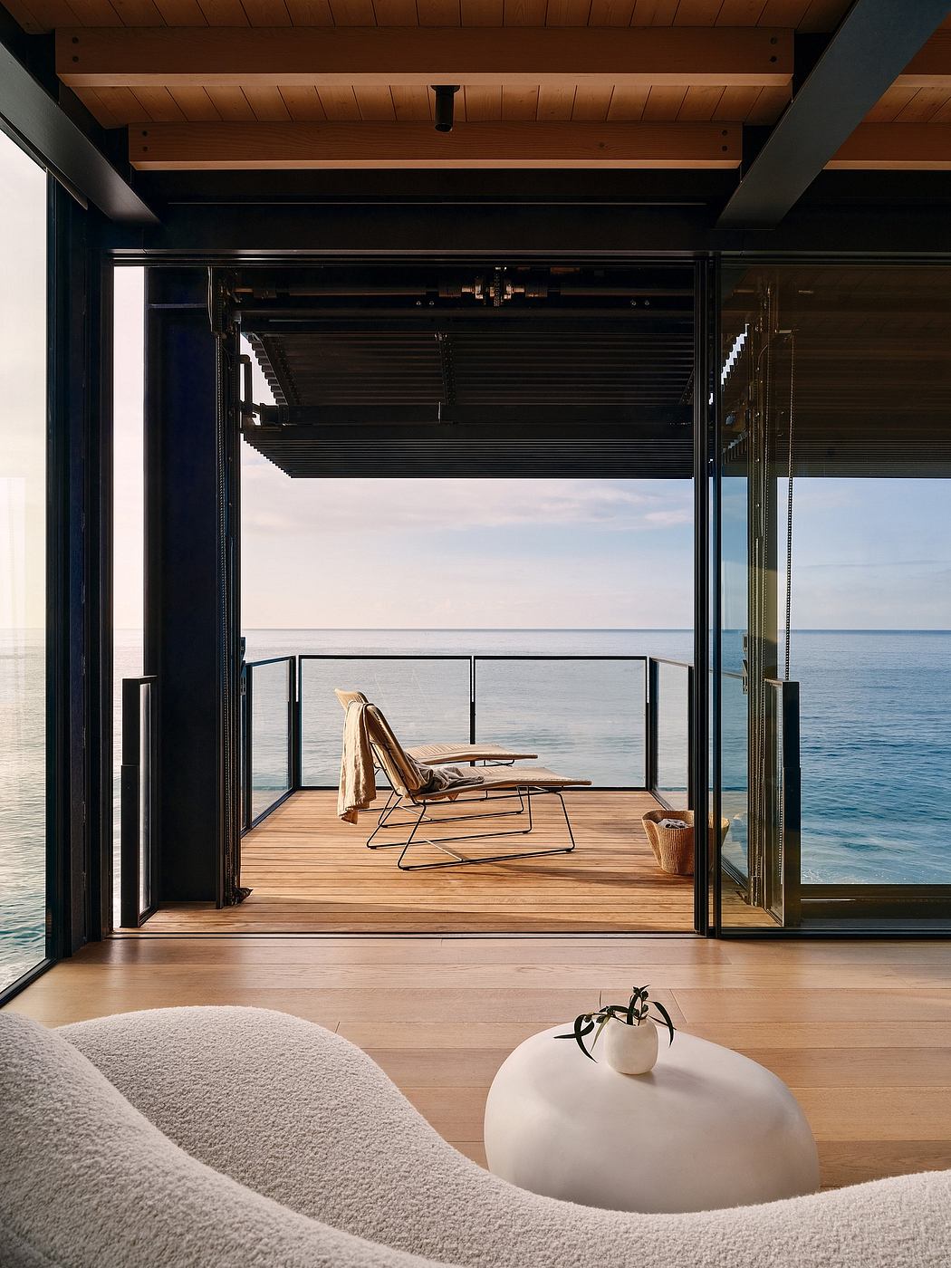 A modern, minimalist room with expansive glass doors overlooking the serene ocean.