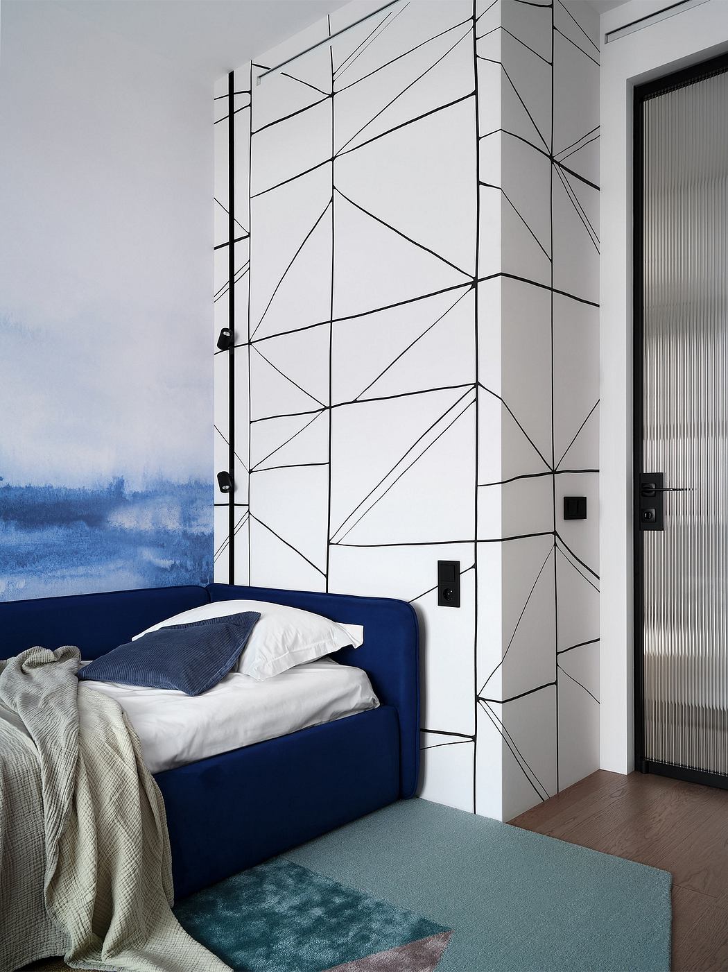 Geometric, minimalist wall design with contrasting blue bed and plush area rug.