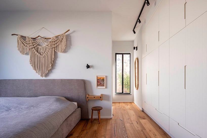 Calming bedroom with macrame wall hanging, wood floors, and built-in cabinetry.
