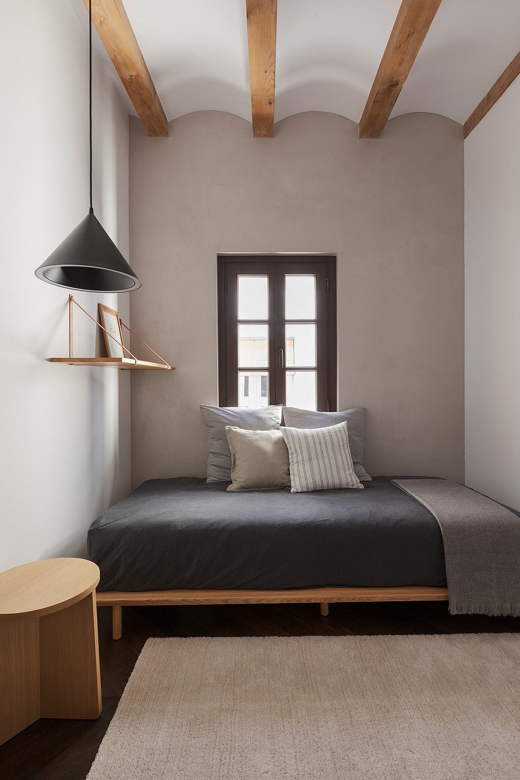 Serene bedroom with exposed wood beams, minimal decor, and black platform bed.