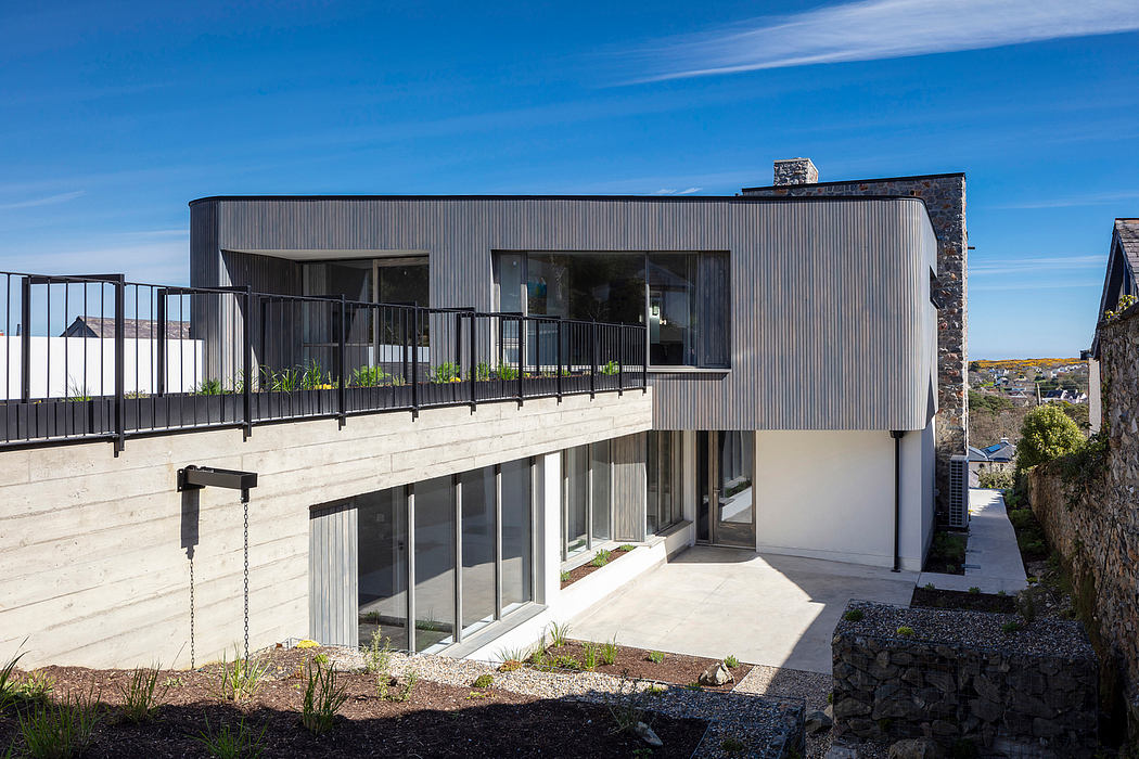 Modern architectural design featuring sleek exterior, balcony, and large windows overlooking landscape.