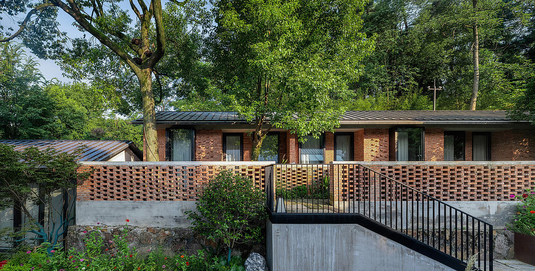A single-story brick building with a slanted roof, surrounded by lush greenery.