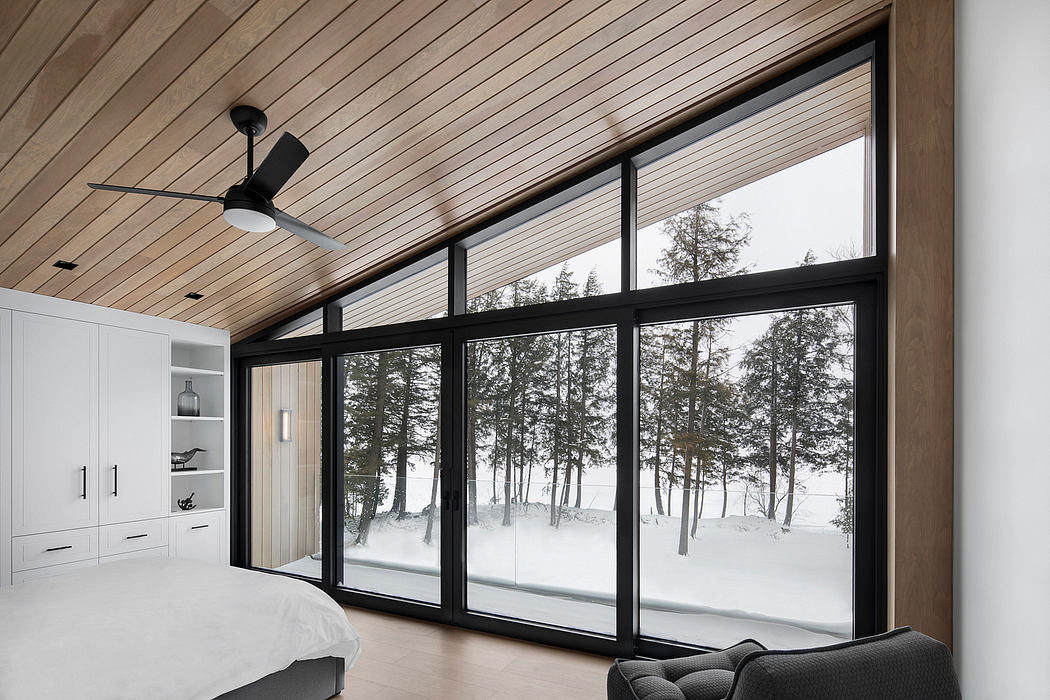 Expansive windows offer panoramic views of the snow-covered forest in this cozy cabin.