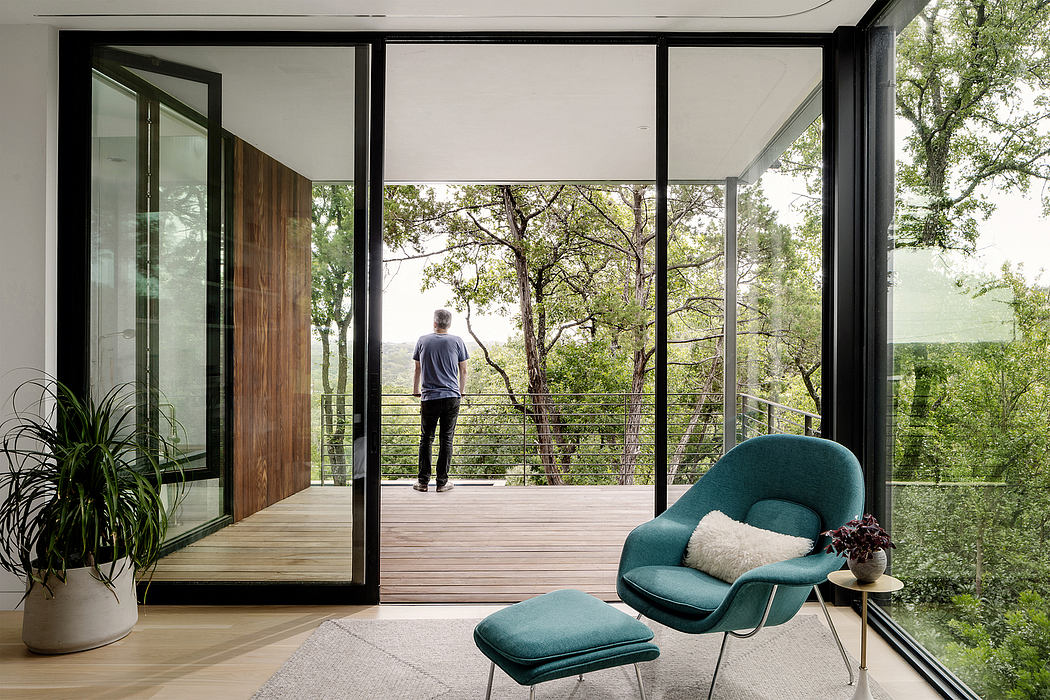 Minimalist modern interior with sweeping forest views, comfortable armchair, and wooden accents.