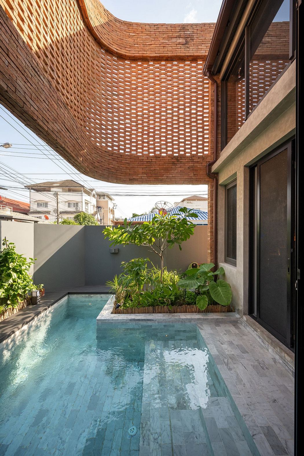 Vibrant brick arch ceiling frames a lush garden and inviting swimming pool.