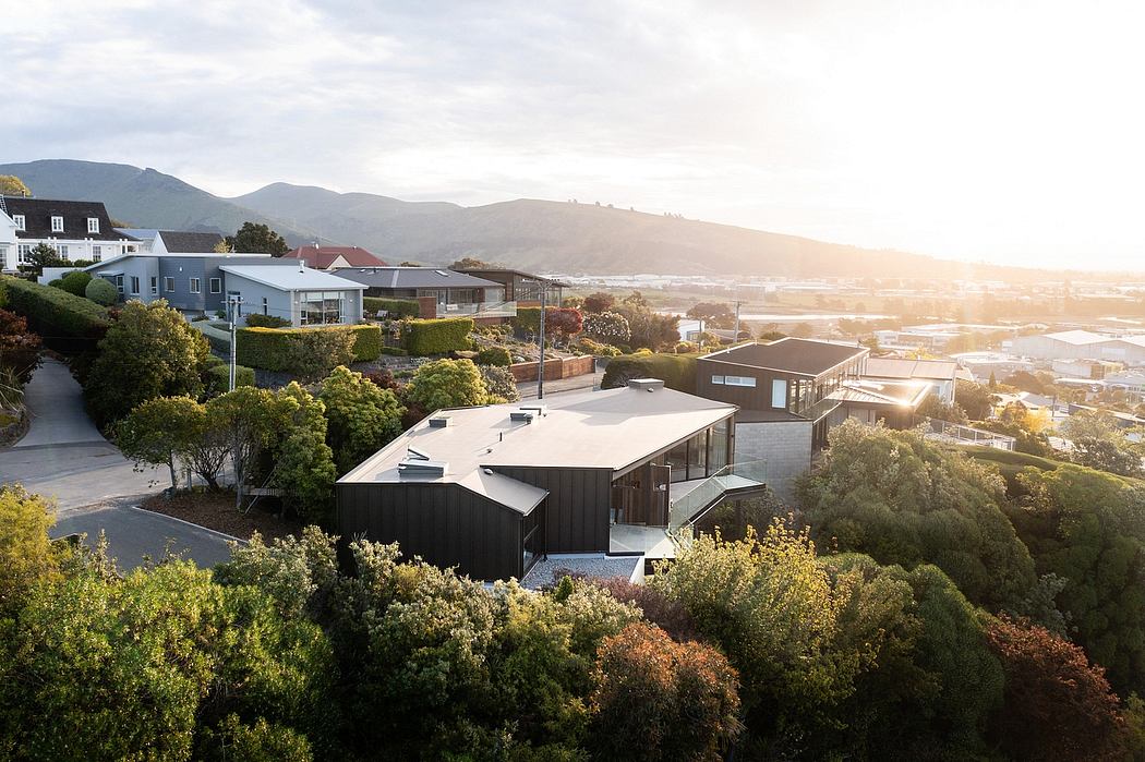 Scenic modern architecture nestled in lush greenery and rolling hills at sunset.