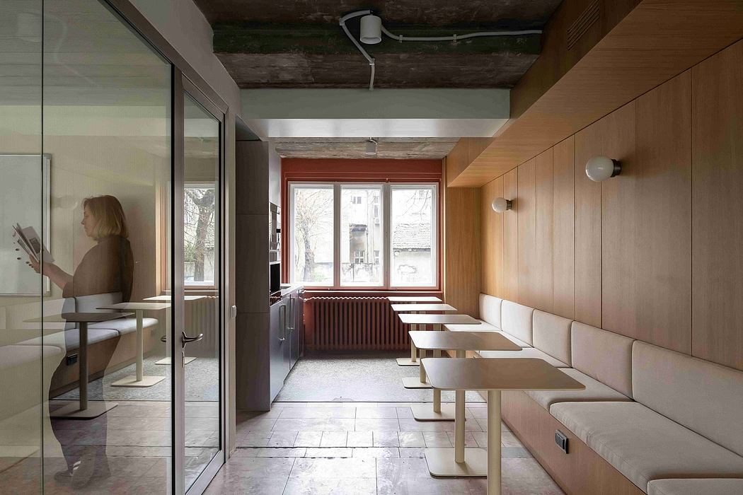 A modern, minimalist interior with wooden paneling, large windows, and simple furniture.