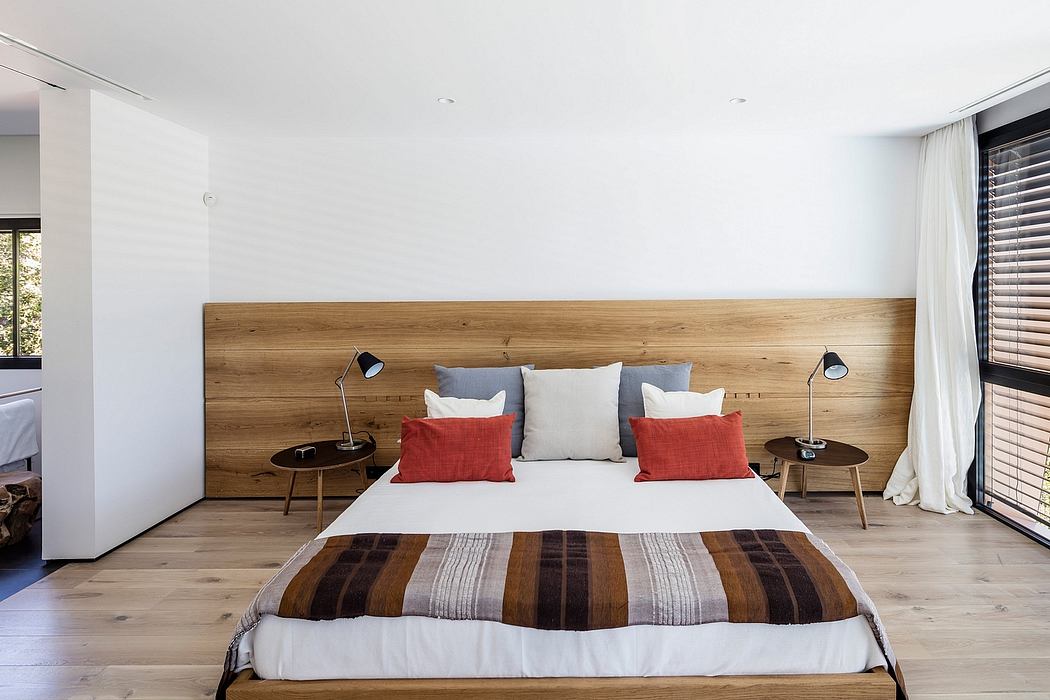 Modern bedroom with wooden accent wall, minimal decor, and large windows for natural light.