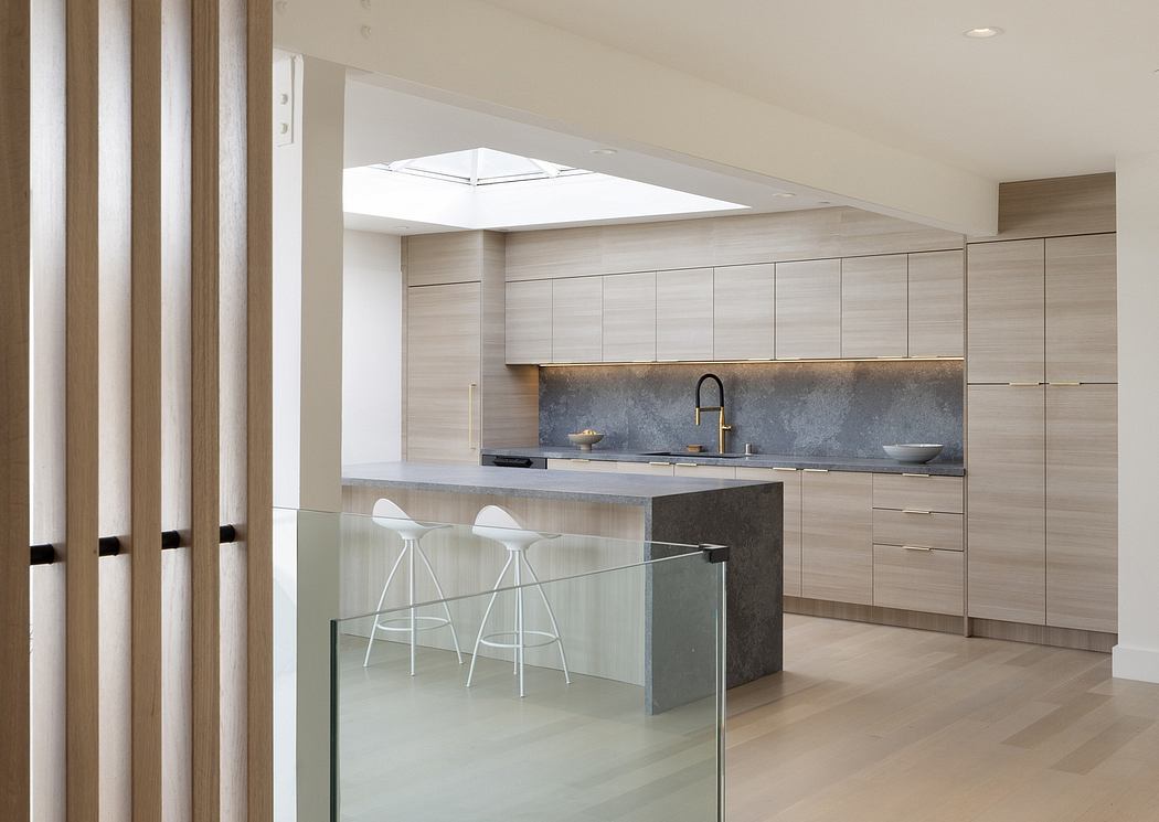 Minimalist kitchen design with wood-paneled cabinets, concrete countertops, and glass divider.