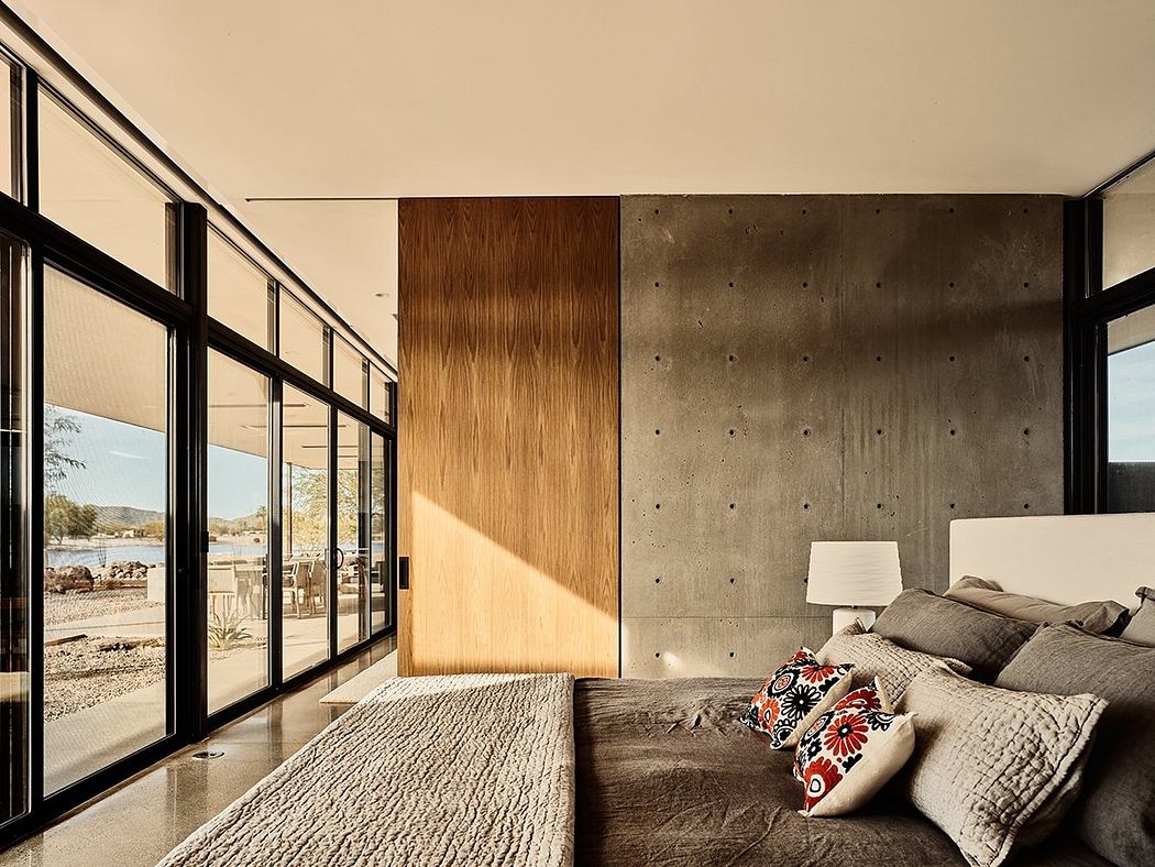Modern, minimalist bedroom with large windows, concrete walls, and wooden paneling.