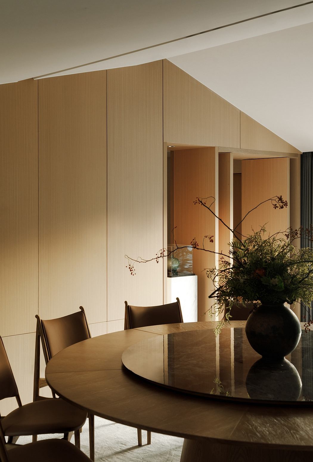 Minimalist dining room with wooden panels, sleek furniture, and decorative floral arrangement.