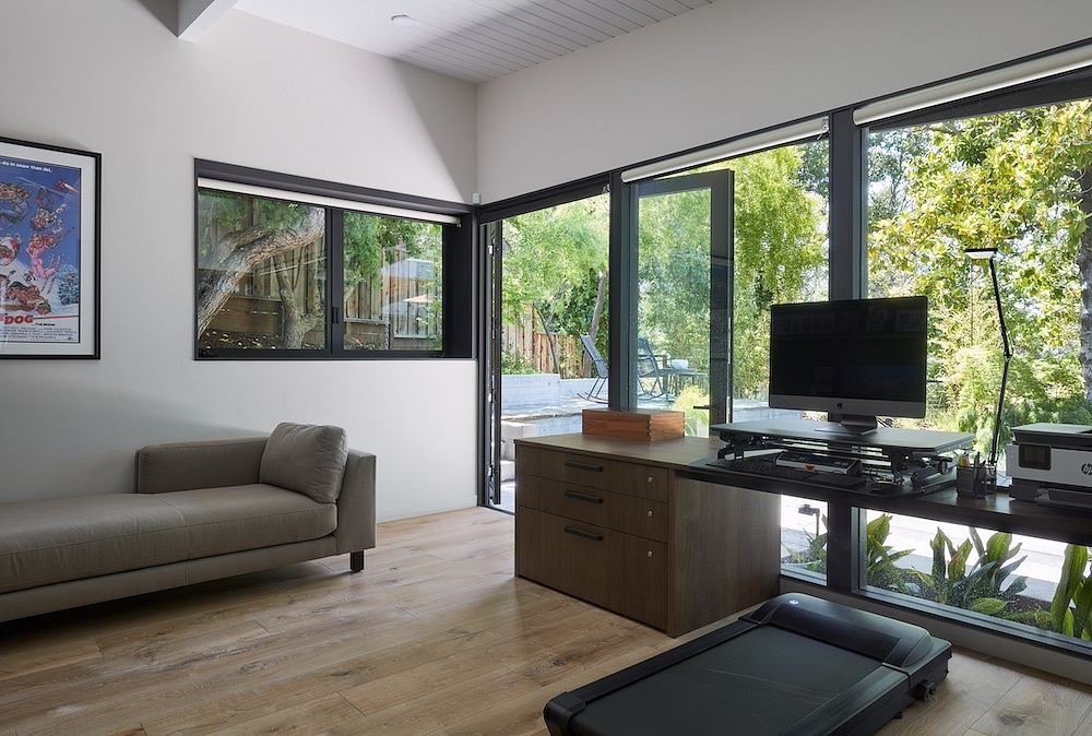 Bright, minimalist living space with large windows overlooking lush greenery outside.