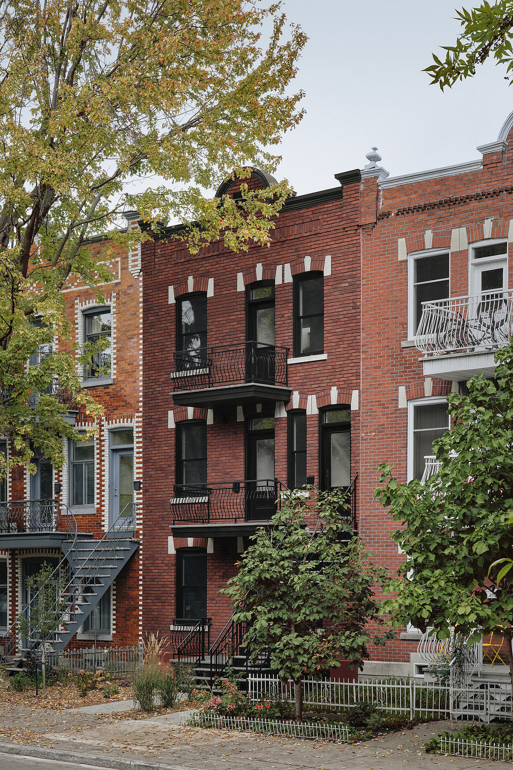 Multistory brick building with arched windows, intricate facade details, and surrounding foliage.