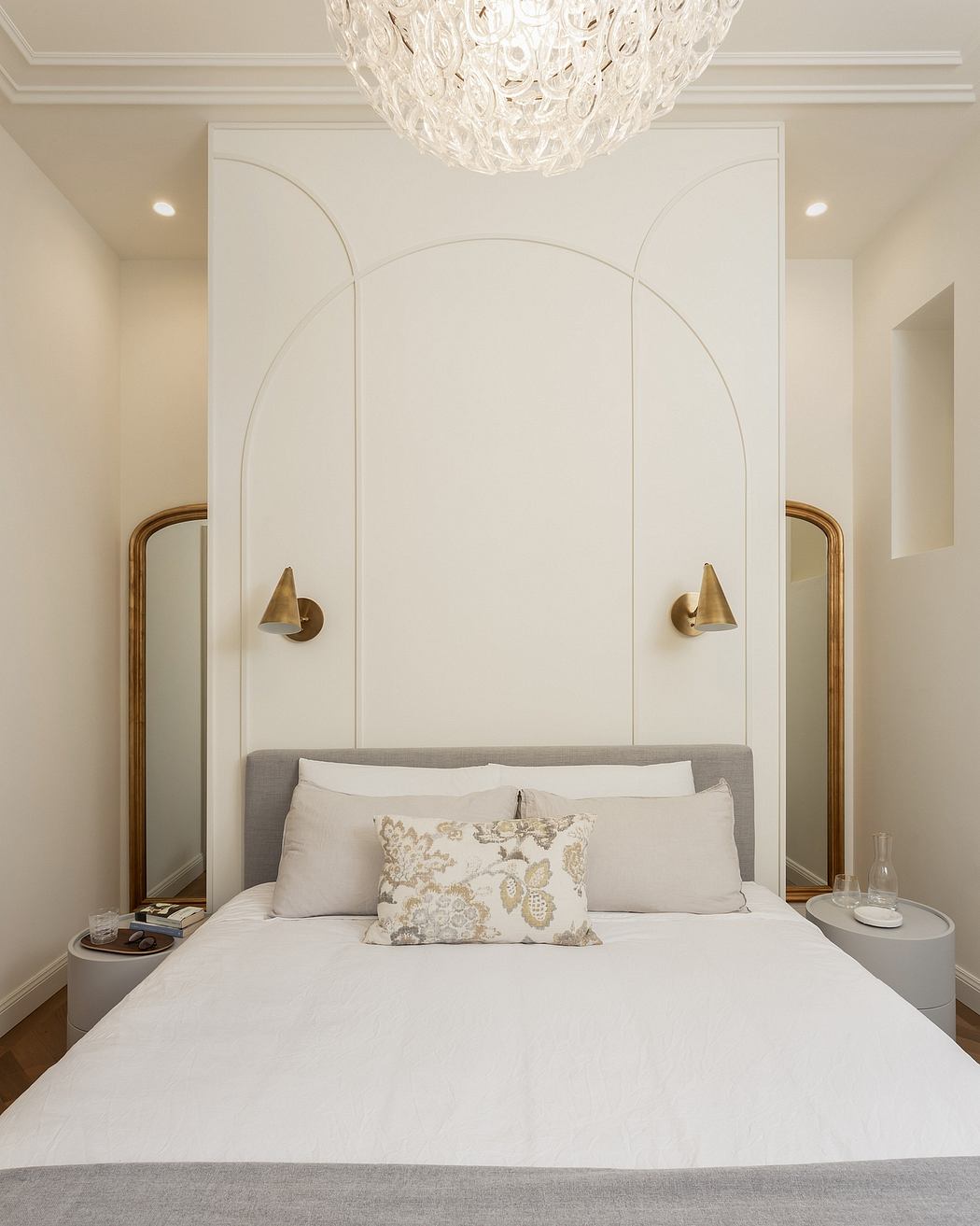 Elegant bedroom with arched alcoves, brass sconces, and a luxurious chandelier.