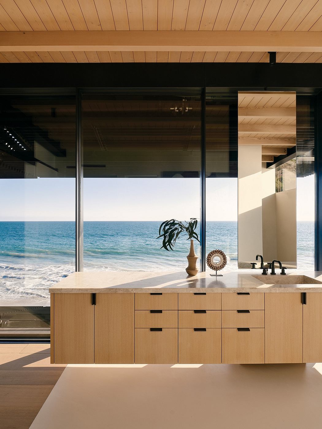 Stunning modern kitchen with expansive ocean view, sleek wood cabinetry, and minimalist decor.