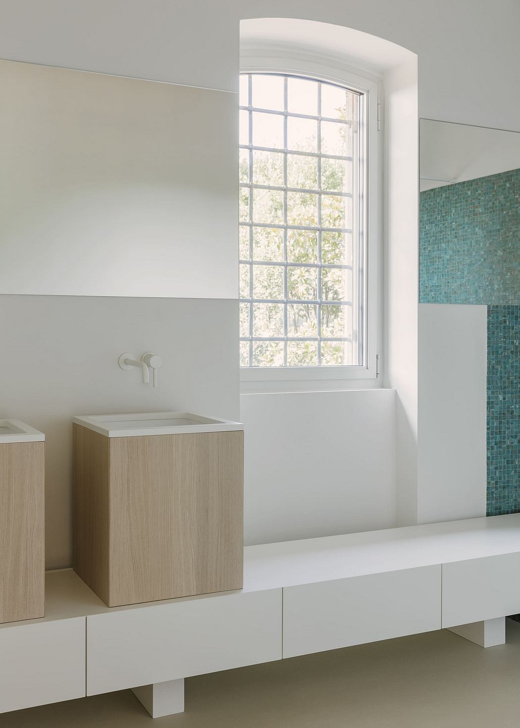 Sleek, minimalist bathroom with arched window, wooden vanity, and teal mosaic tiles.