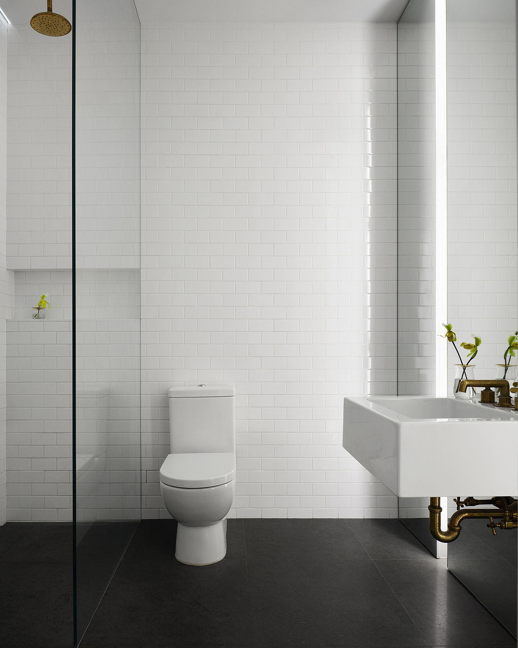 A modern bathroom with clean white tiles, a freestanding sink, and a minimalist toilet.