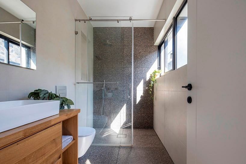 Spacious bathroom with stone-tiled walls, recessed lighting, and a wooden vanity.