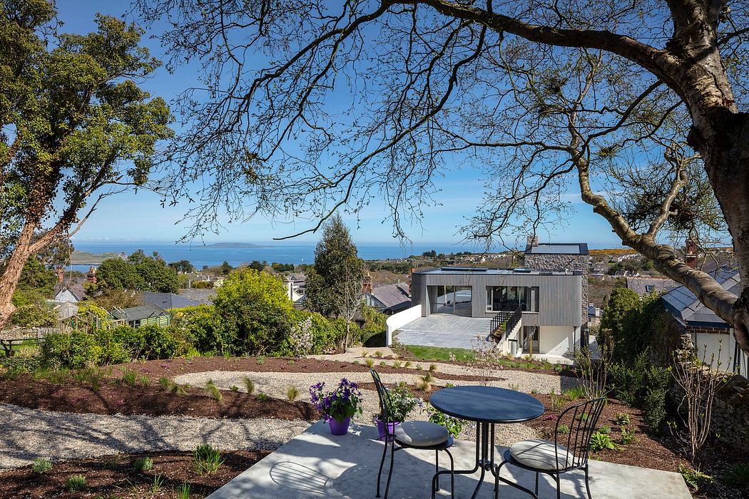 Modern home with wooden exterior, tranquil outdoor seating area, and scenic ocean view.
