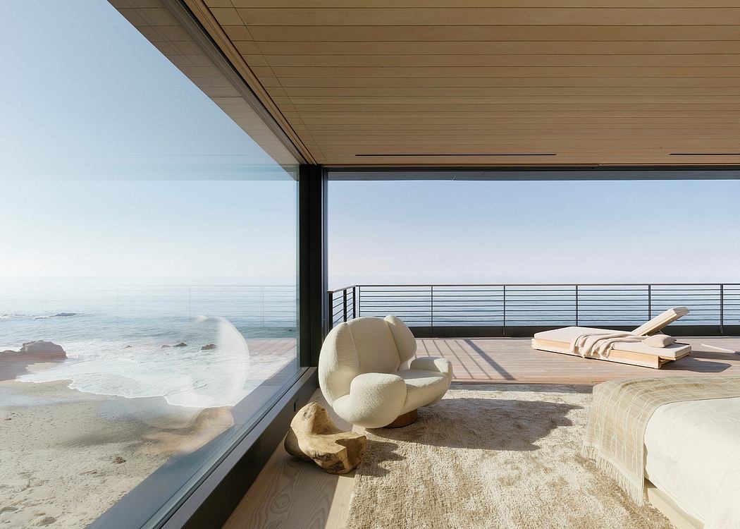 Minimalist beach home with large glass windows, sleek wooden interiors, and a cozy lounge chair.