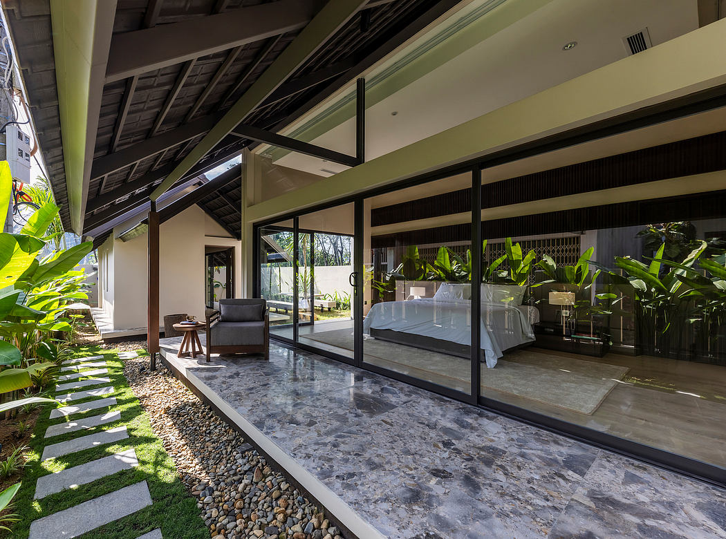 Spacious tropical villa with floor-to-ceiling glass walls, polished stone floors, and lush greenery.