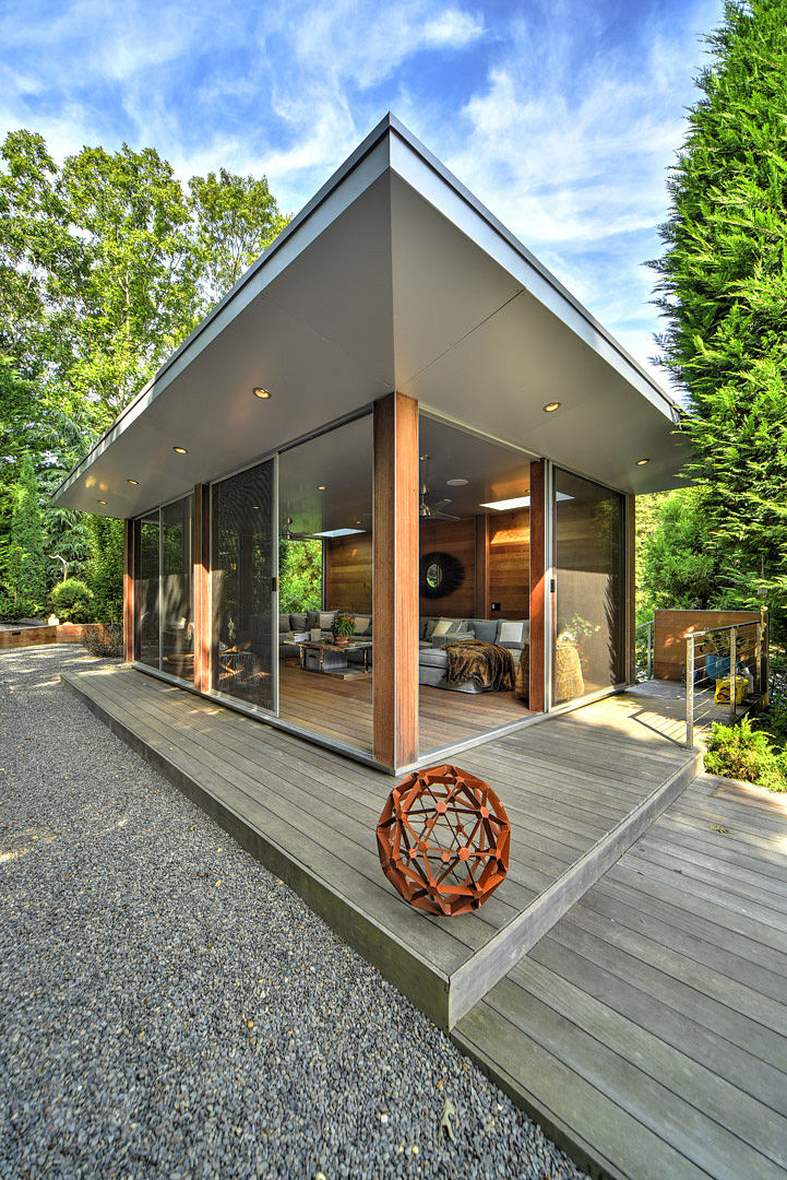 Minimalist modern design with large glass windows, wooden accents, and geometric sculpture.