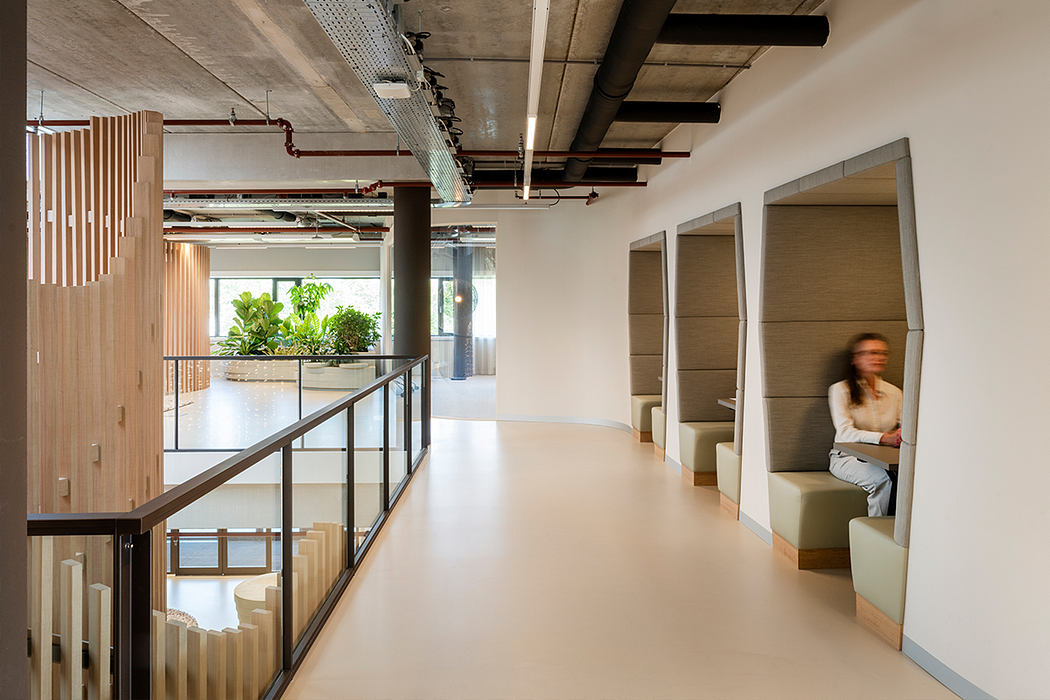 Spacious open-plan office with exposed concrete ceiling, wooden accents, and potted plants.