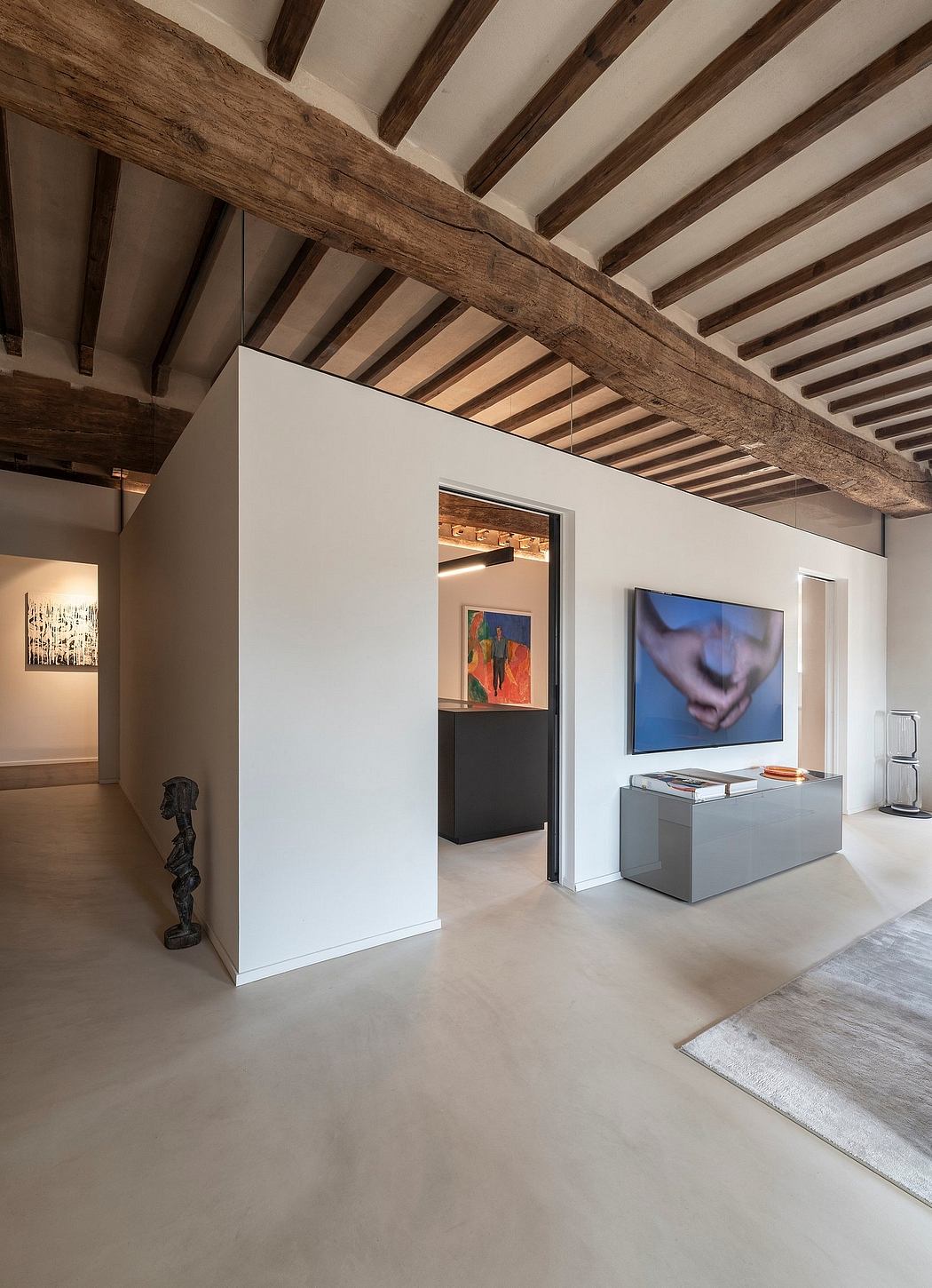 Rustic wooden beams contrast with modern white walls and minimalist furnishings.