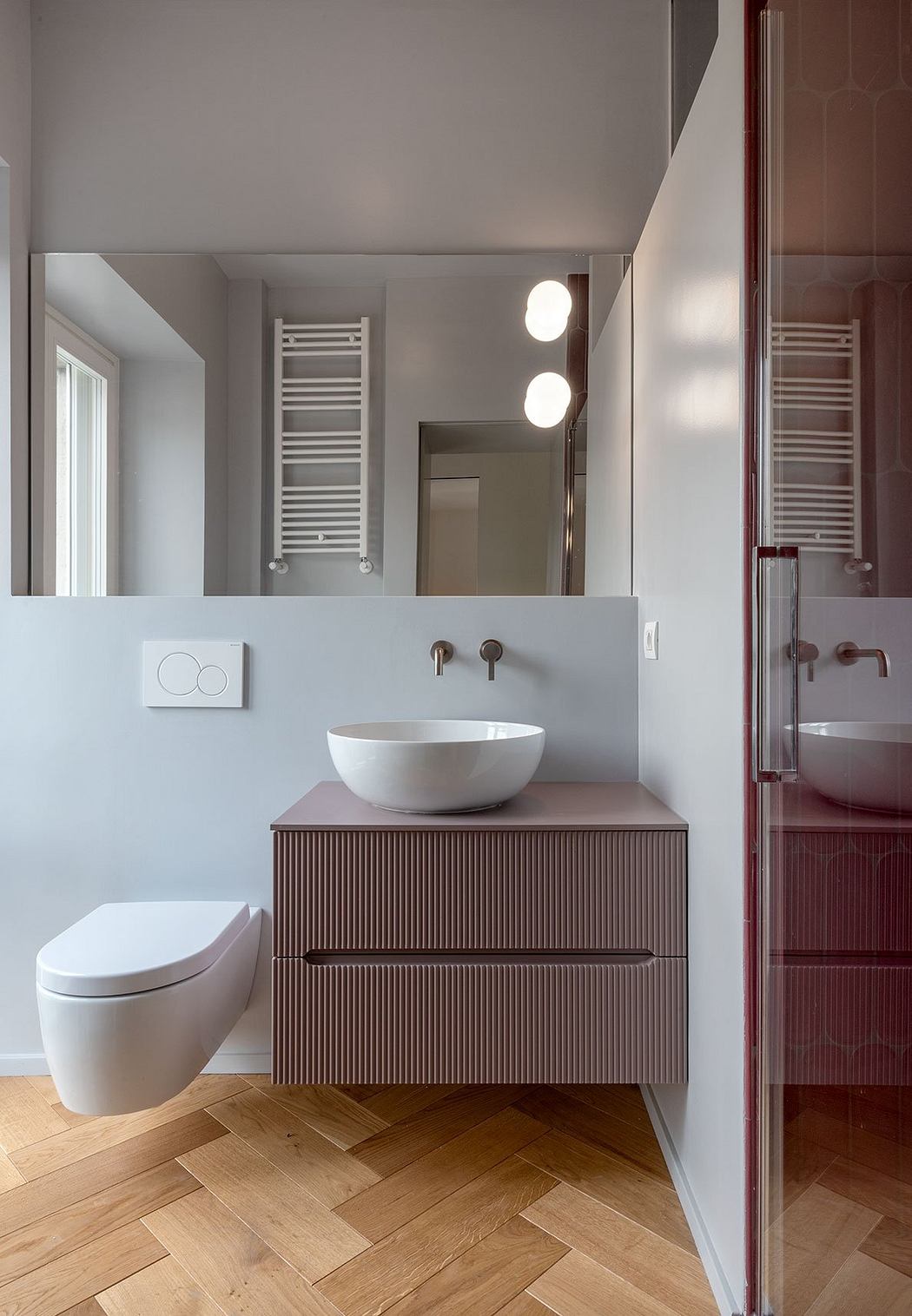 Modern bathroom with sleek vanity, vessel sink, and herringbone wood flooring.