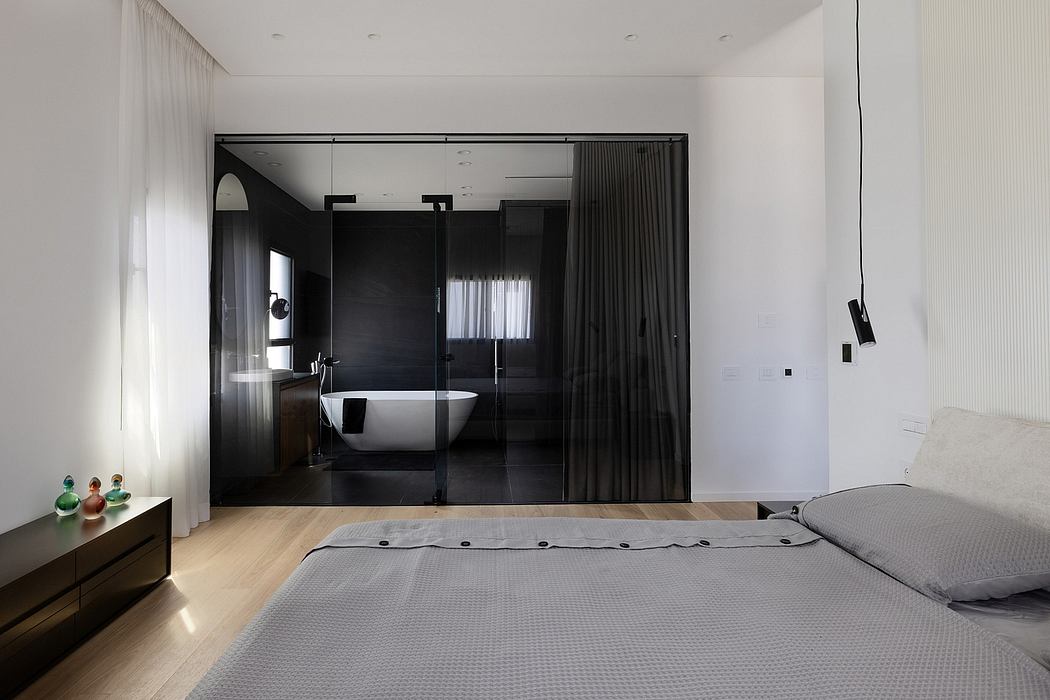 Modern, minimalist bedroom with sleek black bathroom, wooden flooring, and curtains creating a serene atmosphere.