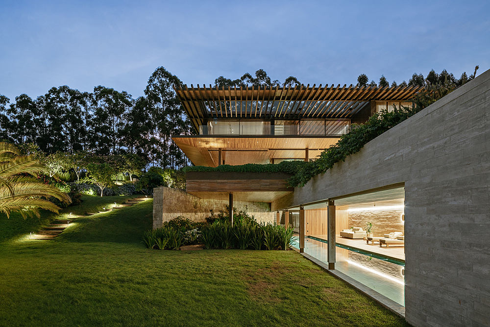 Stunning modern home with sleek concrete walls, exposed wooden beams, and lush green surroundings.