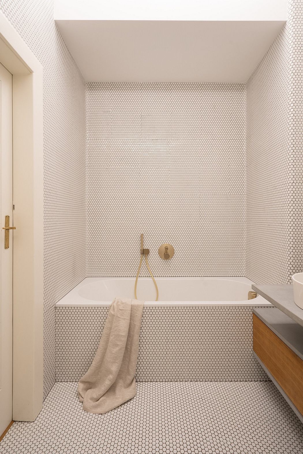 A bathroom with a tiled wall featuring a hexagonal tile pattern and brass fixtures.