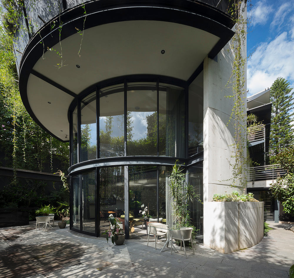 Striking curved glass facade and modern architecture with lush greenery.