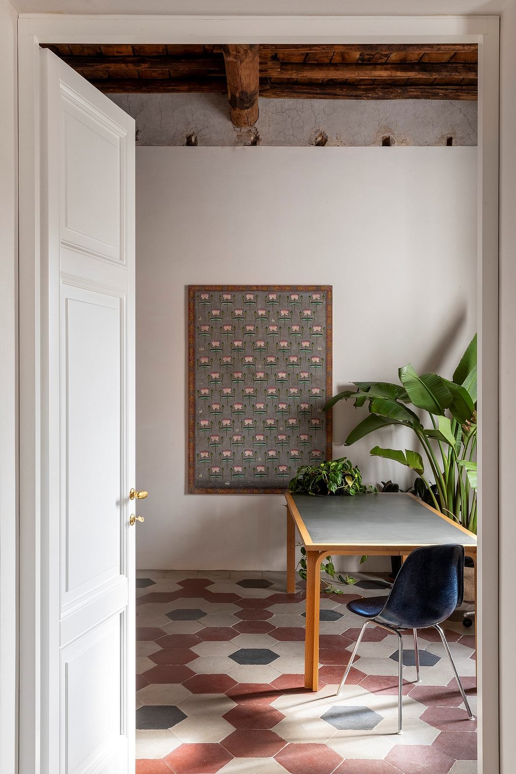 Rustic wood beams, patterned tiled floor, and a desk with potted plants in a cozy room.