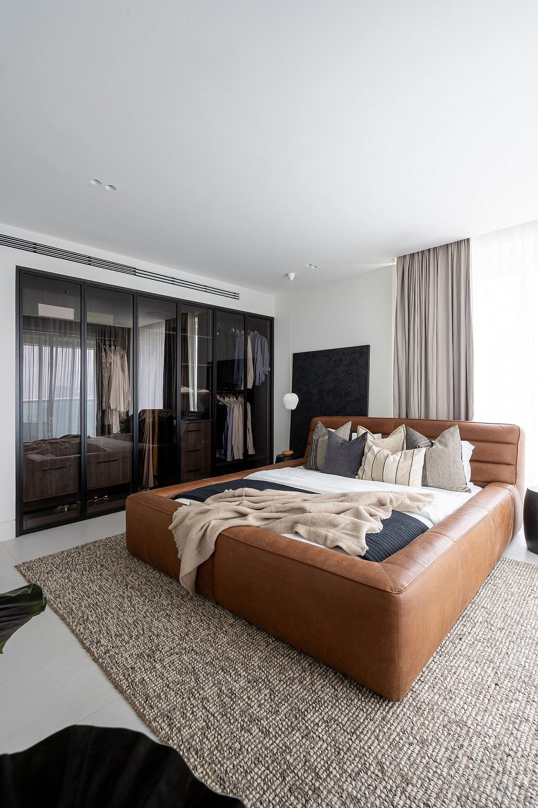 Luxurious modern bedroom with leather sofa, glass wardrobe, and plush rug.