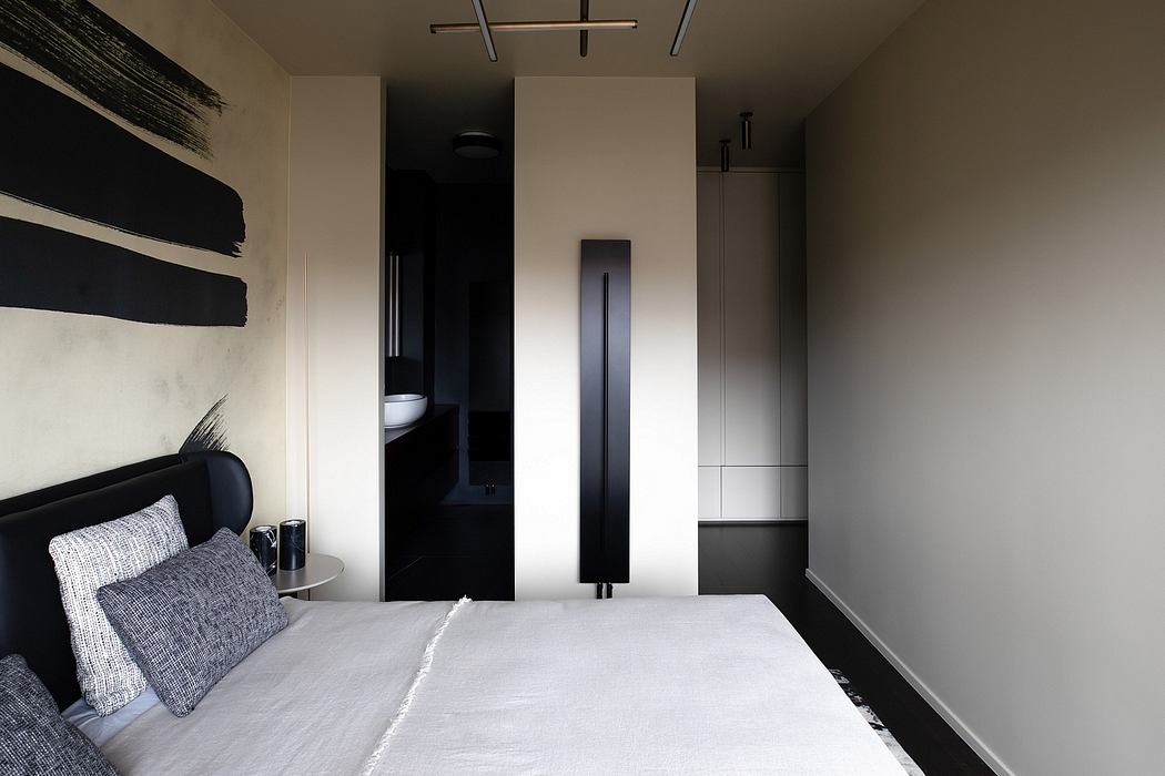 Modern bedroom with sleek black and white design, featuring a minimalist lighting fixture and a built-in closet.
