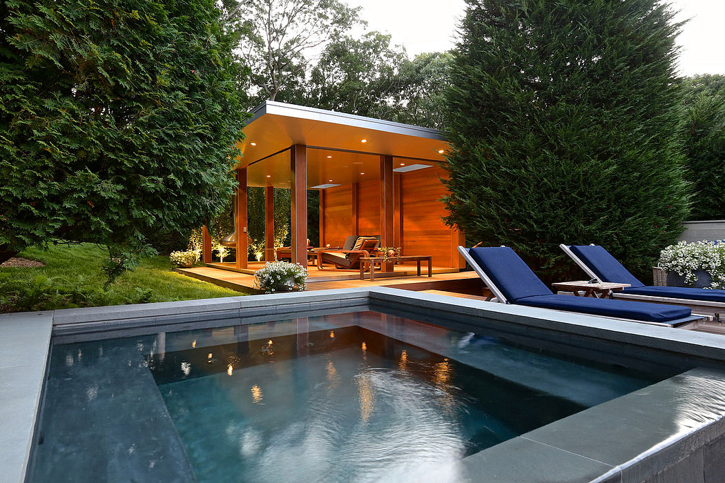 A modern wooden pavilion with floor-to-ceiling glass walls next to a sleek swimming pool.