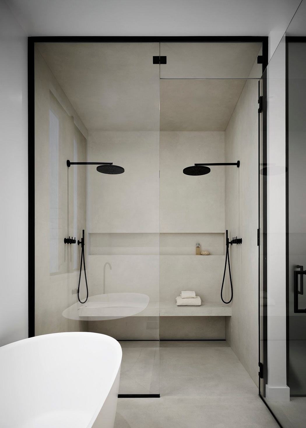 Minimalist bathroom design with freestanding tub, dual walk-in showers, and sleek black fixtures.
